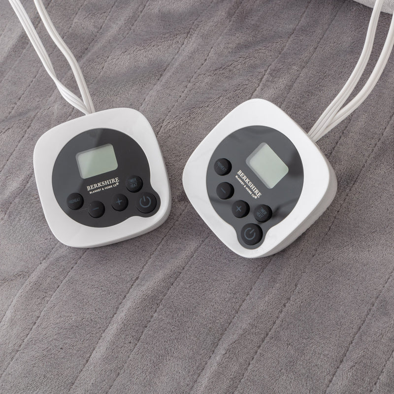 Two digital thermometers on a grey blanket surface
