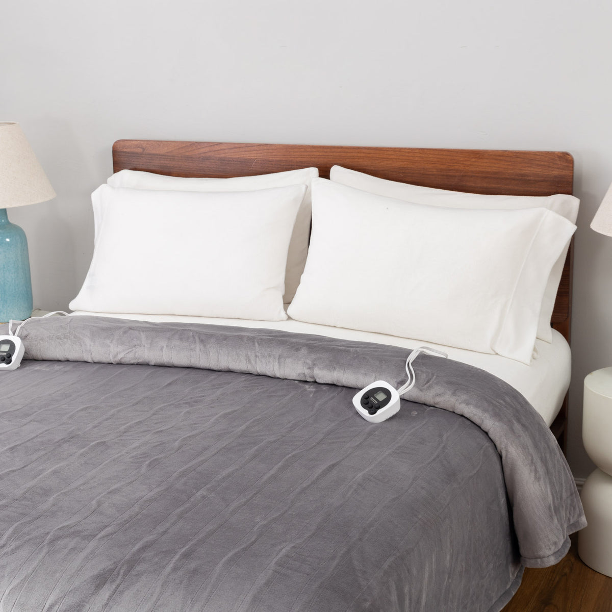 Gray electric blanket on a bed with white pillows and a wooden headboard.