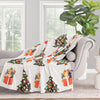 Decorative blanket with Christmas tree and gift design draped over a chair in a living room.