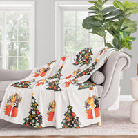 Decorative blanket with Christmas tree and gift design draped over a chair in a living room.