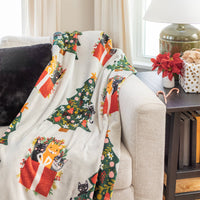 Cat printed holiday throw draped over a beige sofa.