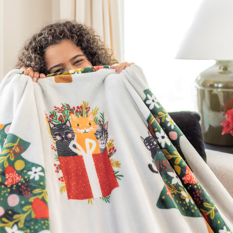A women holding up a cat printed holiday throw.