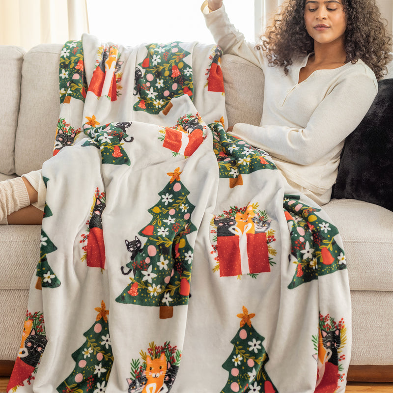 Cat printed holiday throw draped over a womans legs.