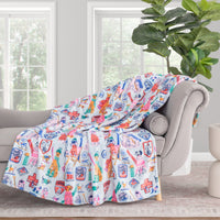 Colorful patterned blanket draped over a gray chair in a room with a plant and window.