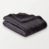 A black velvety plush throw folded neatly on a white surface.