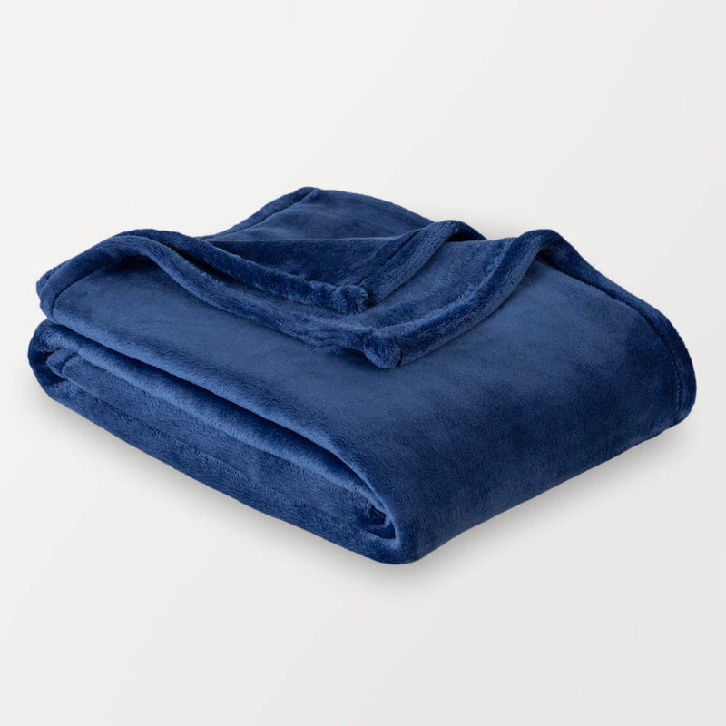 A blue velvety plush throw folded neatly on a white surface.