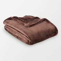 A brown velvety plush throw folded neatly on a white surface.