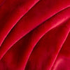 Close up of a neon red velvety throw displaying its smooth and plush texture.