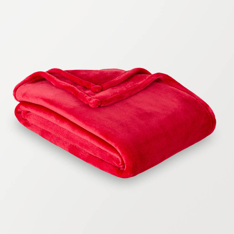 A neon red velvety throw folded neatly on a white surface.