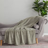 A light green velvety plush throw draped neatly over the arm of a grey chair.