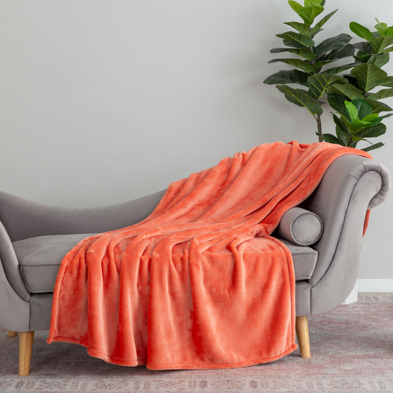 A neon orange velvety throw draped neatly over a grey chair.