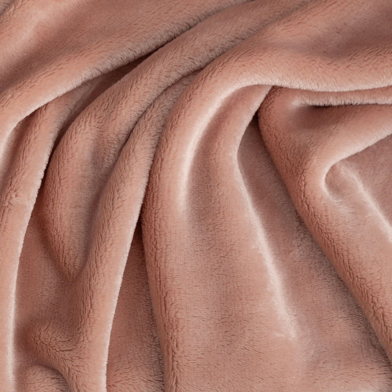 Close up of a blush pink velvety throw displaying its silky smooth and plush texture.