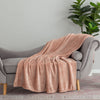 A blush pink velvety throw draped neatly over a grey chair.