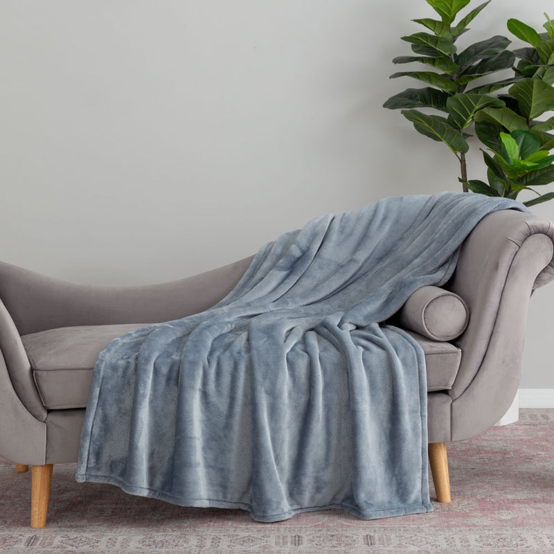 A baby blue velvety plush throw draped neatly over the arm of a grey chair.