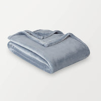 A baby blue velvety plush throw folded neatly on a white surface.