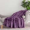 A purple velvety plush throw draped neatly over the arm of a grey chair.