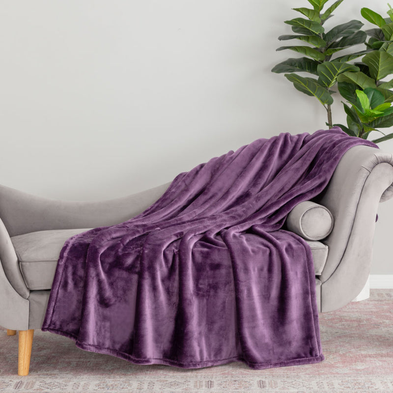 A purple velvety plush throw draped neatly over the arm of a grey chair.