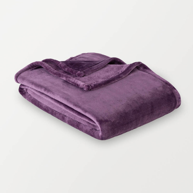 A purple velvety plush throw folded neatly on a white surface.