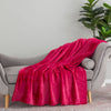 A neon pink velvety throw draped neatly over a grey chair.