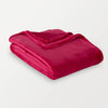 A neon pink velvety throw folded neatly on a white surface.