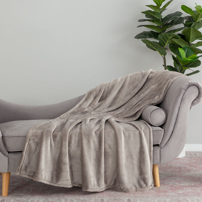 A grey velvety plush throw draped neatly over the arm of a light grey chair.