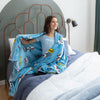 Woman sitting on a bed with a blue cartoon-themed blanket