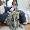 Girl sitting on a bed holding a stuffed dog under a Snoopy blanket with wreath pattern