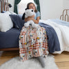 Person holding a Snoopy plush toy on a bed with a Snoopy-themed blanket