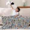 A kid holding a snoopy plush while sitting with a grey peanuts cartoon throw.