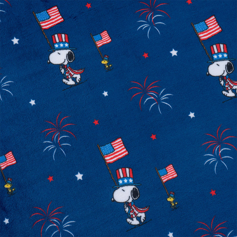 A close up of a cobalt blue Peanuts flag parade throw, displaying the festive print and silky texture.