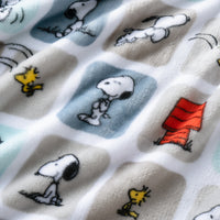 A close up of a blue and grey snoopy block throw displaying the smooth plush texture.