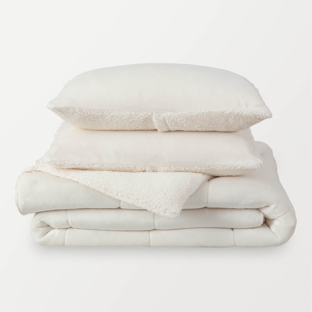 A stack of a white fleece comforter neatly folded on a white background.