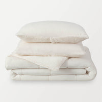 A stack of a white fleece comforter neatly folded on a white background.