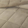 A close-up of a green quilted comforter showing its soft texture and stitching.