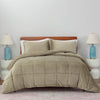 A green quilted comforter draped over a bed with matching taupe pillows and blue lamps on both sides.