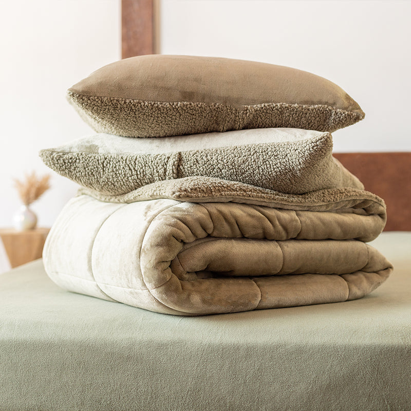 A stack of green comforter sitting on green comforters neatly folded on green fleece sheets.