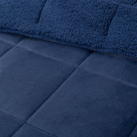 A close-up of a navy quilted comforter showing its stitching details.