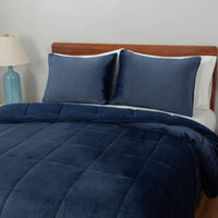 A close-up of a navy quilted comforter showing its stitching details and sherpa reverse.