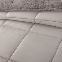 A close-up of a gray quilted comforter showing its soft texture and detailed stitching.