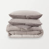 A stack of a grey fleece comforter neatly folded on a white background.