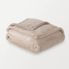 A beige PrimaLush Throw folded neatly on a white surface.