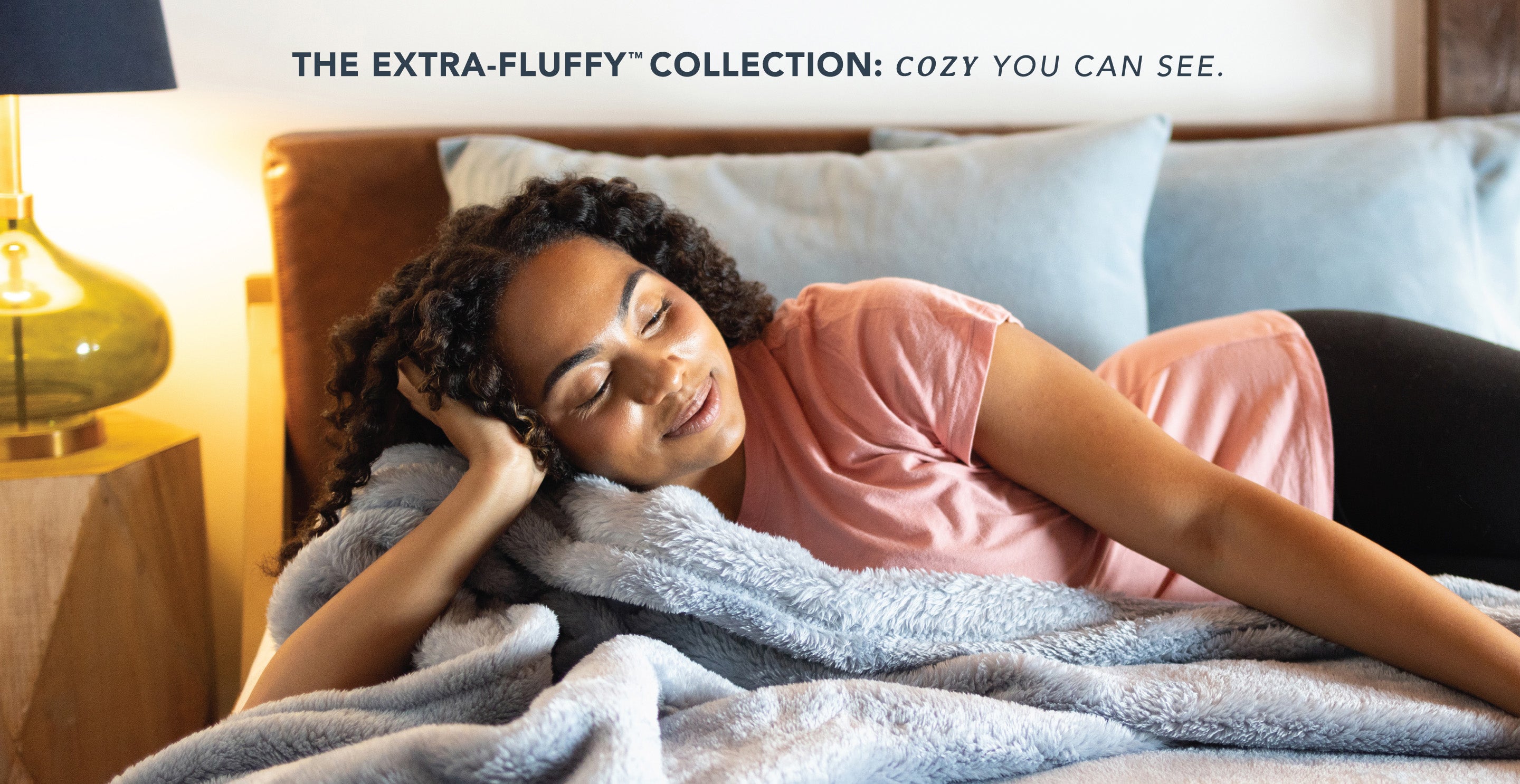 The extra-fluffy collection: cozy you can see. Features a woman laying on our Blue Mist Extra-Fluffy Blanket.