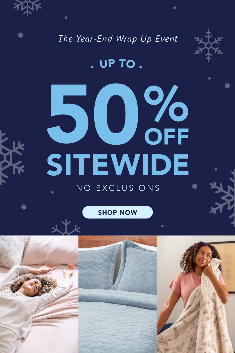 Promotional banner for 'The Year-End Wrap Up Event' with up to 50% off sitewide. Features cozy lifestyle images of people wrapped in soft blankets, folded plush throws in various colors, close-ups of blanket textures, and a serene bedroom scene, highlighting warmth and comfort.