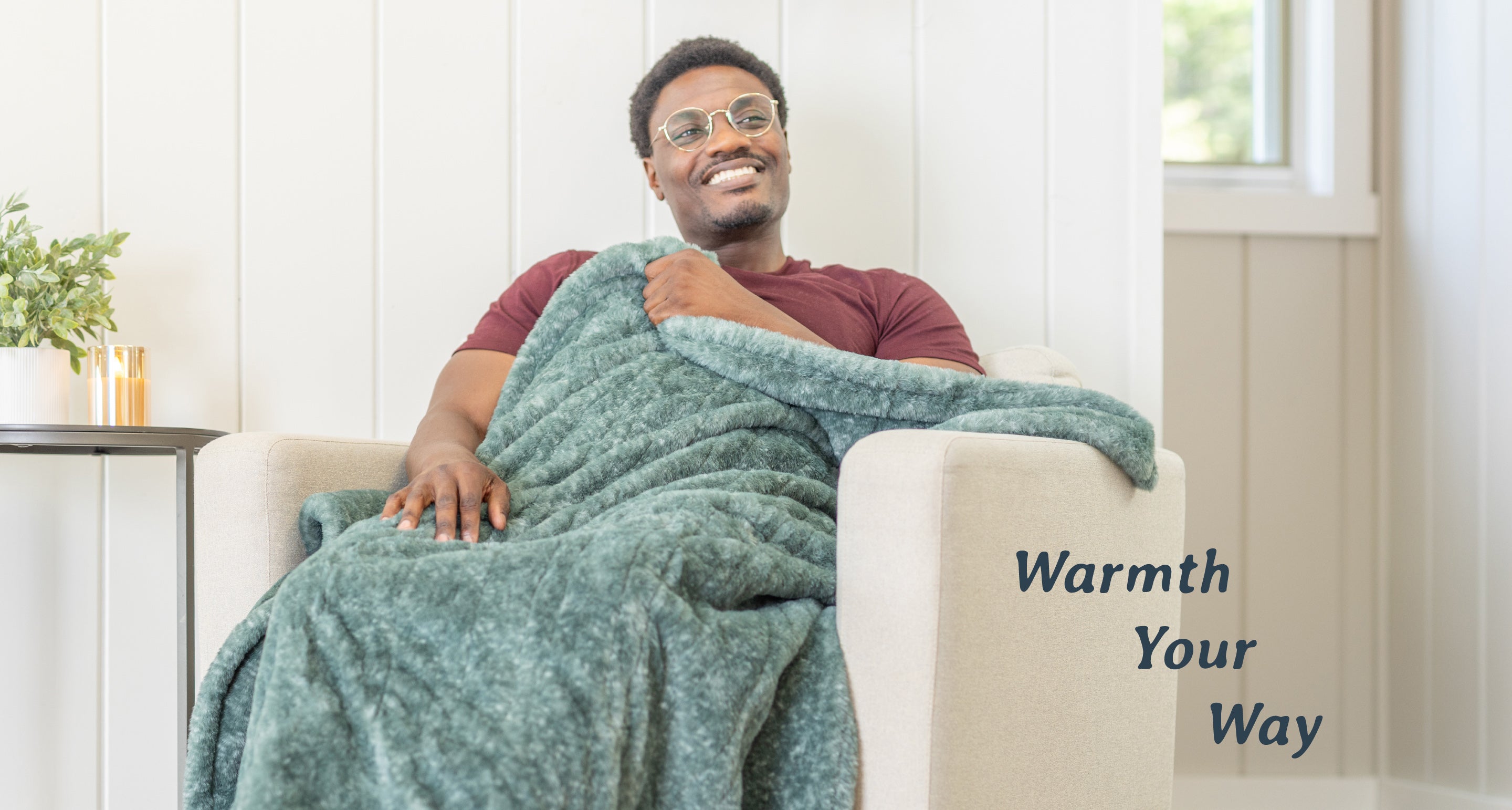 Image of a man sitting in a chair wearing a green heathered faux fur heated throw