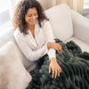 Woman sitting on a couch with a dark green blanket