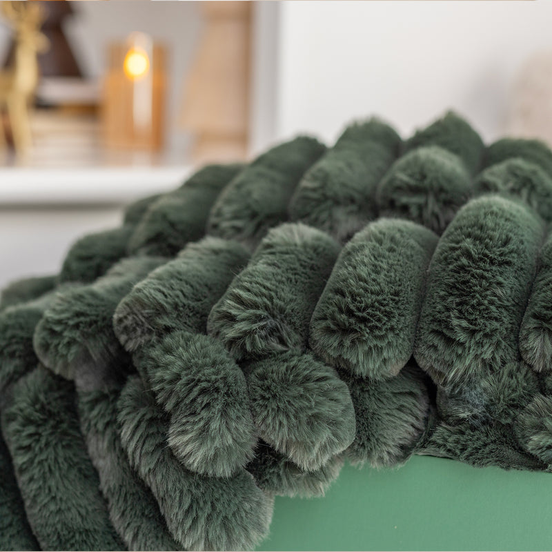 Green fluffy blanket draped over a surface with a blurred indoor background