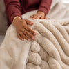 Close-up of a person's hands holding a fluffy beige blanket