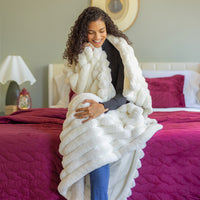 Woman wrapped in a white blanket on a bed with pink bedding