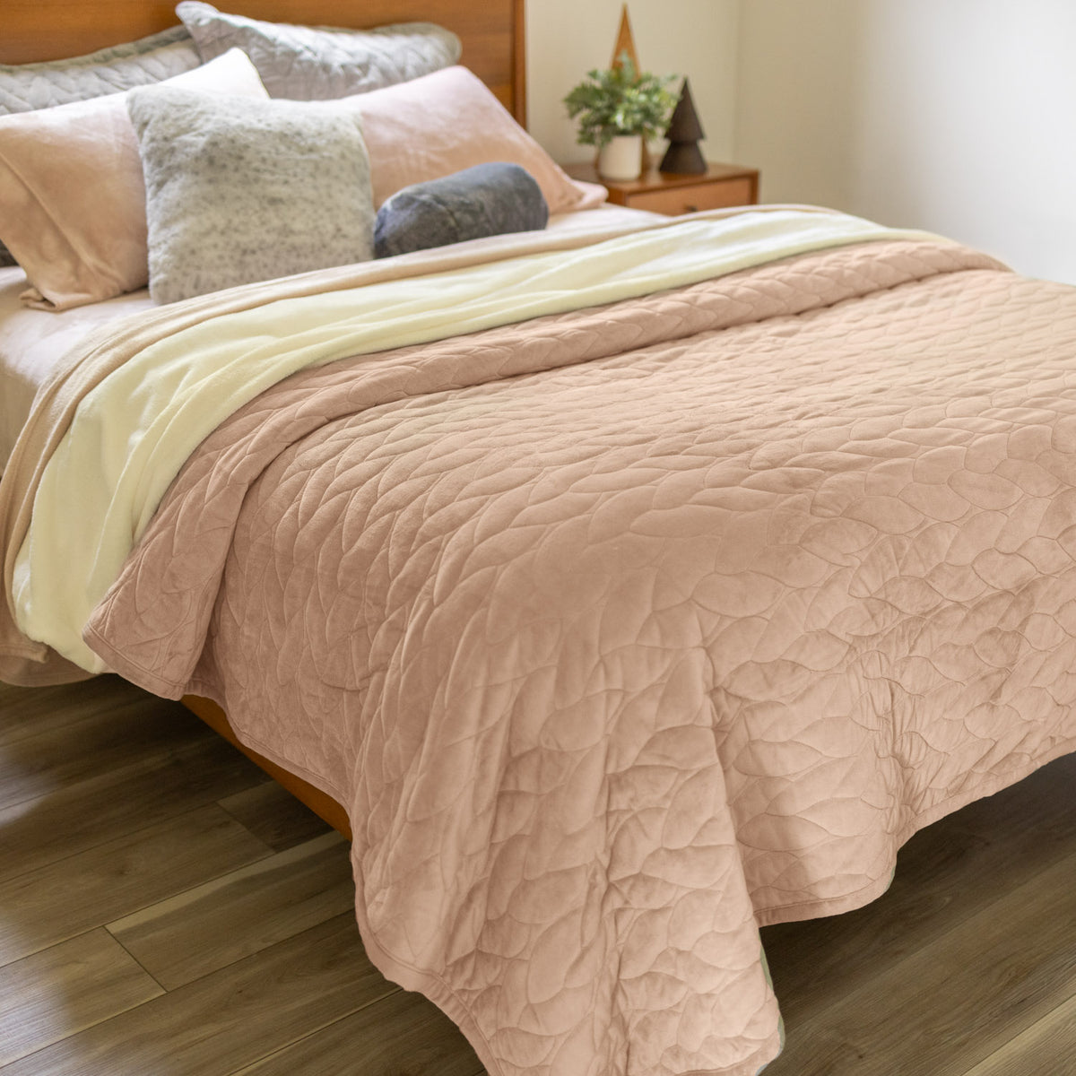 Bed with tan quilt and pillows in a bedroom setting