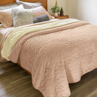 Bed with tan quilt and pillows in a bedroom setting